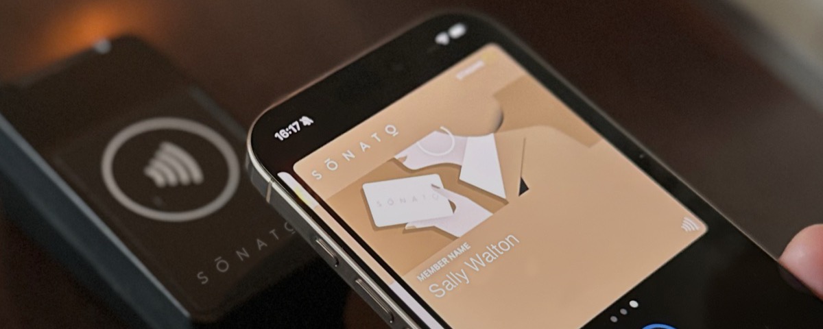 An iPhone with the Sonato membership pass in Apple Wallet, held to the reader at a club door